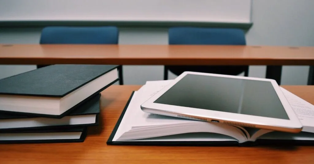 Books and a tablet on a desk in a classroom, depicting modern education.